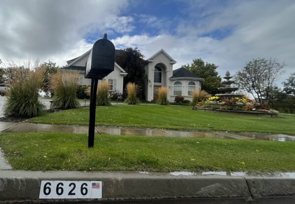 A mailbox in front of a house on the side of a street.